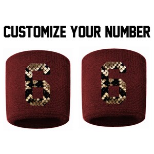 Peut inclure: Deux bracelets de poignet marron avec un numéro "6" à motif peau de serpent sur chacun. Personnalisez votre numéro.