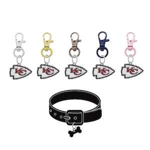 May include: Five different colored dog tags with a Kansas City Chiefs logo. The tags are attached to a black dog collar with a bone charm.