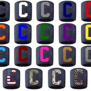 May include: A set of 20 navy blue wristbands with a white letter C in various colors and patterns. The colors include black, white, gray, orange, blue, green, purple, yellow, red, pink, gold, silver, and a camouflage pattern. The patterns include an American flag, a camouflage pattern, a money pattern, and a snake skin pattern.