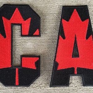 Peut inclure: Deux patchs en feutre, l'un avec une feuille d'érable rouge et la lettre "C" en noir, l'autre avec une feuille d'érable rouge et la lettre "A" en noir.