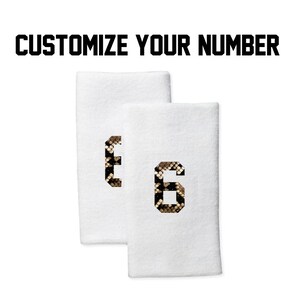 Peut inclure: Deux bracelets blancs avec un numéro 6 imprimé en motif peau de serpent. Personnalisez votre numéro.