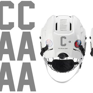 May include: Two white hockey helmets with black face masks and chin straps. One helmet has a gray "C" and the other has a gray "A". Gray letters "C" and "A" are displayed on the left side of the image.