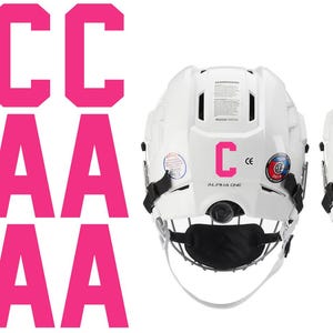 May include: White hockey helmets with black face masks and pink letter decals. The letters "C" and "A" are displayed on the back of the helmets. The image also shows multiple pink "C" and "A" letters.