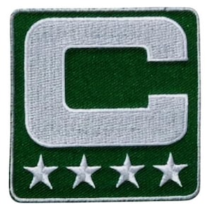 May include: A square, embroidered patch with a white 'C' on a green background, and four white stars below. The patch has a green border. This patch is likely for a sports team or organisation.