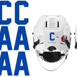 May include: White hockey helmets with black face masks and blue letter decals. The letters include multiple "C" and "A" decals. The helmets have various stickers and the text "ALPHA ONE".