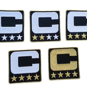May include: Five embroidered patches featuring a black square with a white "C" and five stars below. Four patches have a white "C" and gold stars, while one has a gold "C" and gold stars. The patches are likely for sports or team apparel.