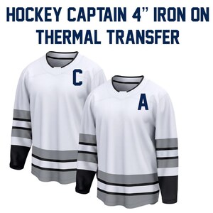 May include: Two white hockey jerseys with black and gray accents. One jersey has a large blue "C" on the chest, the other has a blue "A". The text "HOCKEY CAPTAIN 4" IRON ON THERMAL TRANSFER" is at the top.