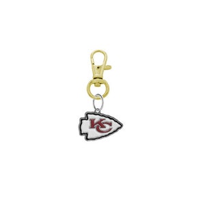 May include: A gold metal keychain with a silver arrowhead charm featuring the Kansas City Chiefs logo. The logo is red and white with the letters "KC" in the center.