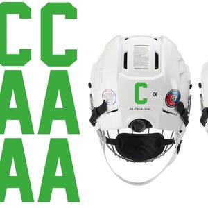May include: White hockey helmets with black face masks. One helmet has a green "C" and the other a green "A". Green "C" and "A" letters are also displayed. The helmets have the text "ALPHA ONE".