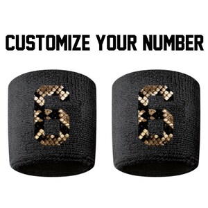Peut inclure: Deux bracelets noirs avec un numéro six à motif peau de serpent sur chacun. Les bracelets sont à personnaliser avec votre propre numéro.