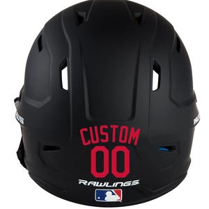 May include: Black baseball helmet with the word "CUSTOM" and the number "00" in red. The Rawlings logo and a Major League Baseball logo are also visible.