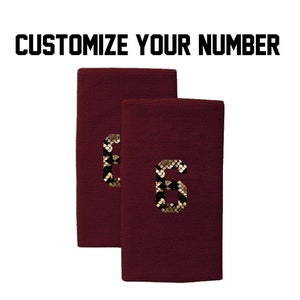 Peut inclure: Deux bandeaux de transpiration marron avec un numéro "6" en motif peau de serpent or et noir sur chacun.