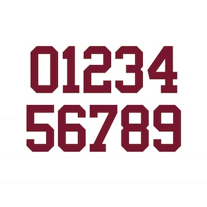 May include: A set of maroon-colored numbers from zero to nine, displayed in a bold, blocky font. The numbers are arranged in two rows on a white background, with the top row displaying 0, 1, 2, 3, and 4, and the bottom row showing 5, 6, 7, 8, and 9.