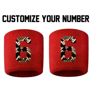 Peut inclure: Deux bracelets rouges avec un numéro six à motif peau de serpent sur chacun. Personnalisez votre numéro.