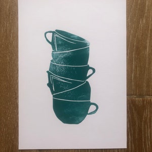 May include: A stack of four teal green ceramic mugs with white outlines. The mugs are stacked on top of each other, with the top mug upside down.