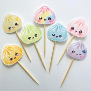 Może przedstawiać: Zestaw sześciu dekoracyjnych wykałaczek do jedzenia z ilustracjami pierożków w stylu kawaii w różnych pastelowych kolorach, w tym żółtym, zielonym, tęczowym, niebieskim, różowym i fioletowym. Każdy pierożek ma uśmiechniętą buzię i drewniany patyczek.