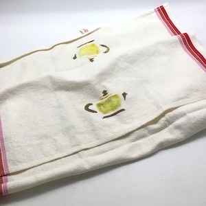 May include: A white tea towel with red and pink stripes along the edge. The towel has two brown and yellow teapots printed on it.