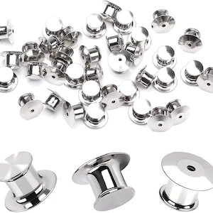 May include: A large quantity of silver-toned metal pin back closures. The closures are made of two parts: a round base with a small hole in the center and a cylindrical post that fits into the base. The closures are commonly used for attaching badges, pins, and other small items to clothing or fabric.