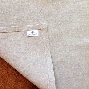 May include: A close-up of a light gray linen kitchen towel with a white label that says "G&T Design".