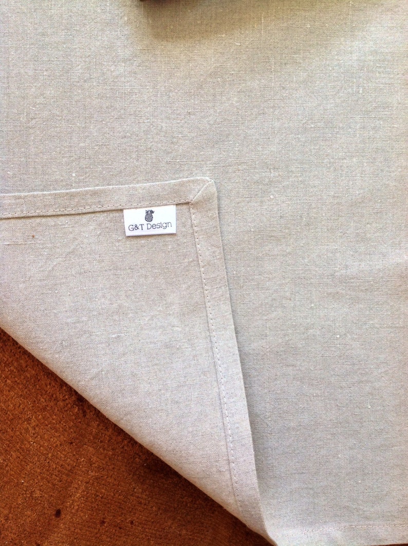 May include: A close-up of a light gray linen kitchen towel with a white label that says "G&T Design".