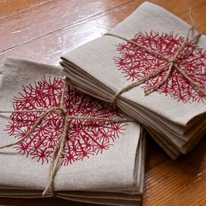 May include: A stack of linen napkins with a red floral design. The napkins are tied together with twine.