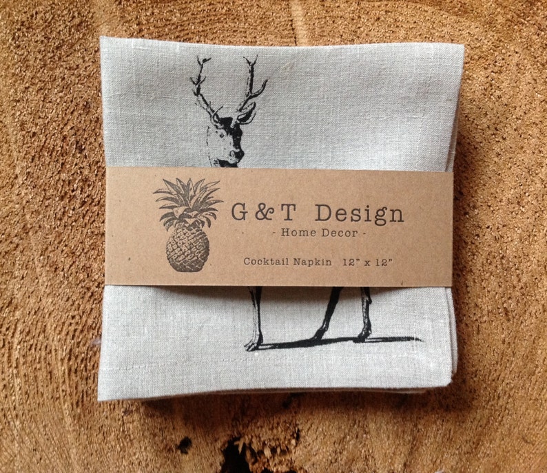 May include: Set of four linen cocktail napkins with a black and white deer print. The napkins are packaged with a brown label that reads "G&T Design - Home Decor - Cocktail Napkin 12" x 12" ".