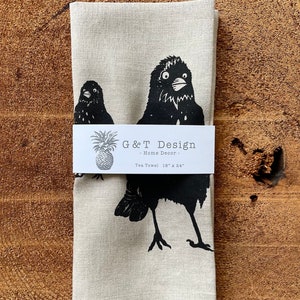 May include: A linen tea towel with a black and white illustration of two birds. The towel is 18 inches by 24 inches and has a label that reads "G&T Design - Home Decor - Tea Towel 18" x 24".