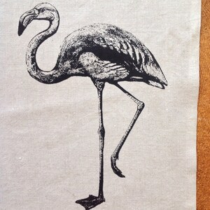 May include: Black and white illustration of a flamingo standing on one leg on a beige background.