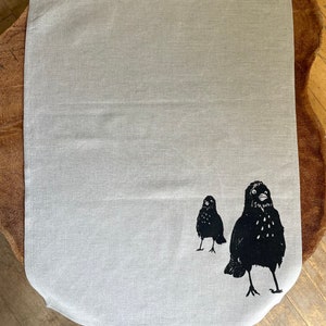 May include: A white linen tea towel with a black silhouette of two birds printed on it.