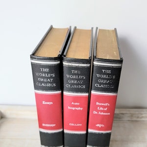 May include: Three hardcover books with black spines and red covers. The books are part of a series called "The World's Great Classics". The titles are "Essays" by Emerson, "Auto-biography" by Cellini, and "Boswell's Life of Dr. Johnson".