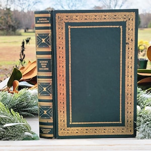 May include: A hardcover book titled "Echoes From The Macabre" by Daphne Du Maurier. The book has a dark green cover with gold decorative borders and accents. The spine features gold lettering and decorative elements. The book is part of the International Collectors Library.