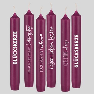 May include: Set of six purple candles with white text. The text on the candles reads: "GLUCKSKERZE", "Heute ist mein Lieblingstag", "DAS LEBEN IST sch&ouml;n", "Leben, lieben, lachen", "GUTE LAUNE Kerze", and "GL&Uuml;CKSKERZE".