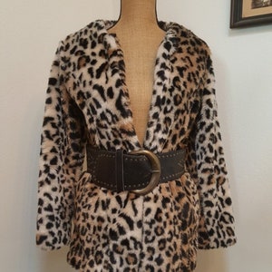May include: A brown, black, and white leopard print faux fur jacket with a brown leather belt with a large silver buckle.