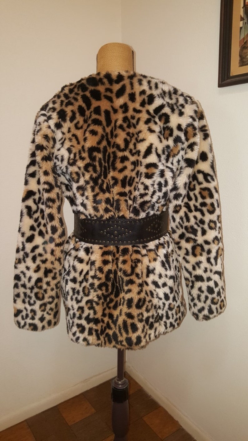 May include: A brown, black, and white leopard print faux fur coat with a black studded belt.
