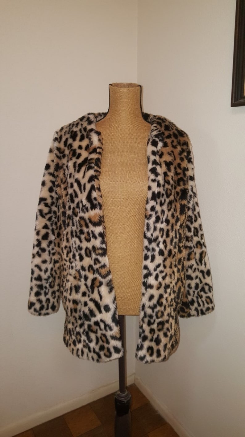 May include: A brown, black, and white leopard print faux fur jacket with a long sleeve and open front.