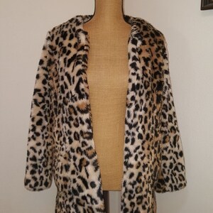 May include: A brown, black, and white leopard print faux fur jacket with a long sleeve and open front.