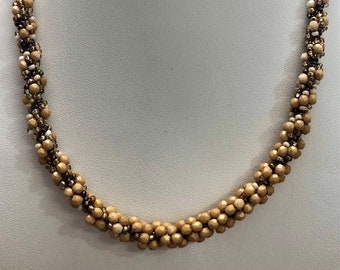 May include: A gold and white beaded necklace with a twisted design.