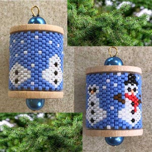 Puede incluir: Adorno navideño hecho a mano con diseño de muñeco de nieve. El adorno cilíndrico está hecho de cuentas azules, blancas y negras, con detalles de madera. Tiene un lazo dorado para colgar y una cuenta azul en la parte inferior.