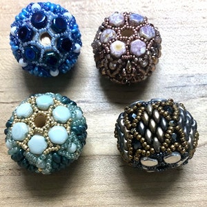 May include: Four beaded spheres with intricate geometric patterns. The beads are in shades of blue, green, brown, and silver.