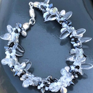 May include: A silver bracelet with clear and black beads in a flower shape.