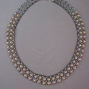 May include: A silver and brown beaded necklace with a delicate design. The necklace is made with small, round beads that are arranged in a repeating pattern. The necklace is approximately 18 inches long and has a lobster claw clasp.