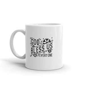May include: White ceramic mug with a black graphic that reads "GOD BLESS US EVERYONE" in a whimsical font. The design includes snowflake and floral accents. The mug has a curved handle and is set against a white background.
