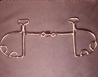May include: A silver-toned metal horse bit with a twisted wire center and curved side pieces. The bit has a symmetrical design with a loop at the top of each side and a series of small loops on the lower portion of each side.