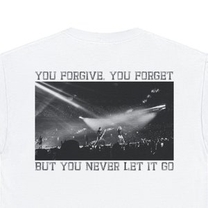 Könnte beinhalten: Weißes T-Shirt mit einem Schwarzweißfoto einer Band, die auf der Bühne spielt. Der Text "YOU FORGIVE. YOU FORGET. BUT YOU NEVER LET IT GO" ist unter dem Foto aufgedruckt.