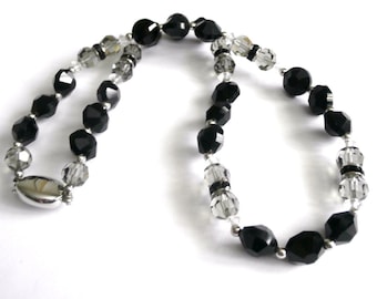 Puede incluir: Un collar de cuentas de cristal negro y transparente con un cierre plateado.