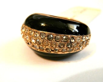 Puede incluir: Un anillo negro con una banda dorada y una fila de diamantes de imitación transparentes alrededor del borde.