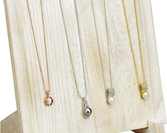 May include: White wooden necklace display stand with five slots for hanging necklaces. The stand has a slanted base and is made of unfinished wood.