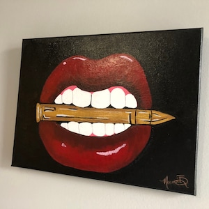 May include: A painting of a pair of red lips with white teeth biting down on a gold bullet. The background is black.