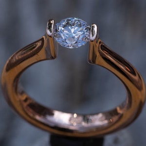 May include: A gold ring with a single, clear, round diamond set in the center.