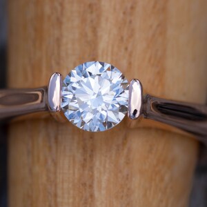 May include: A silver ring with a large, clear, round diamond set in the center.